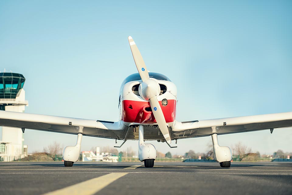 Single-engine training aircraft on the apron in front of an airport control tower