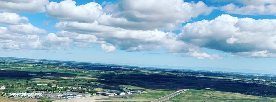 Aerial view of an airfield and the surrounding countryside under scattered cloud